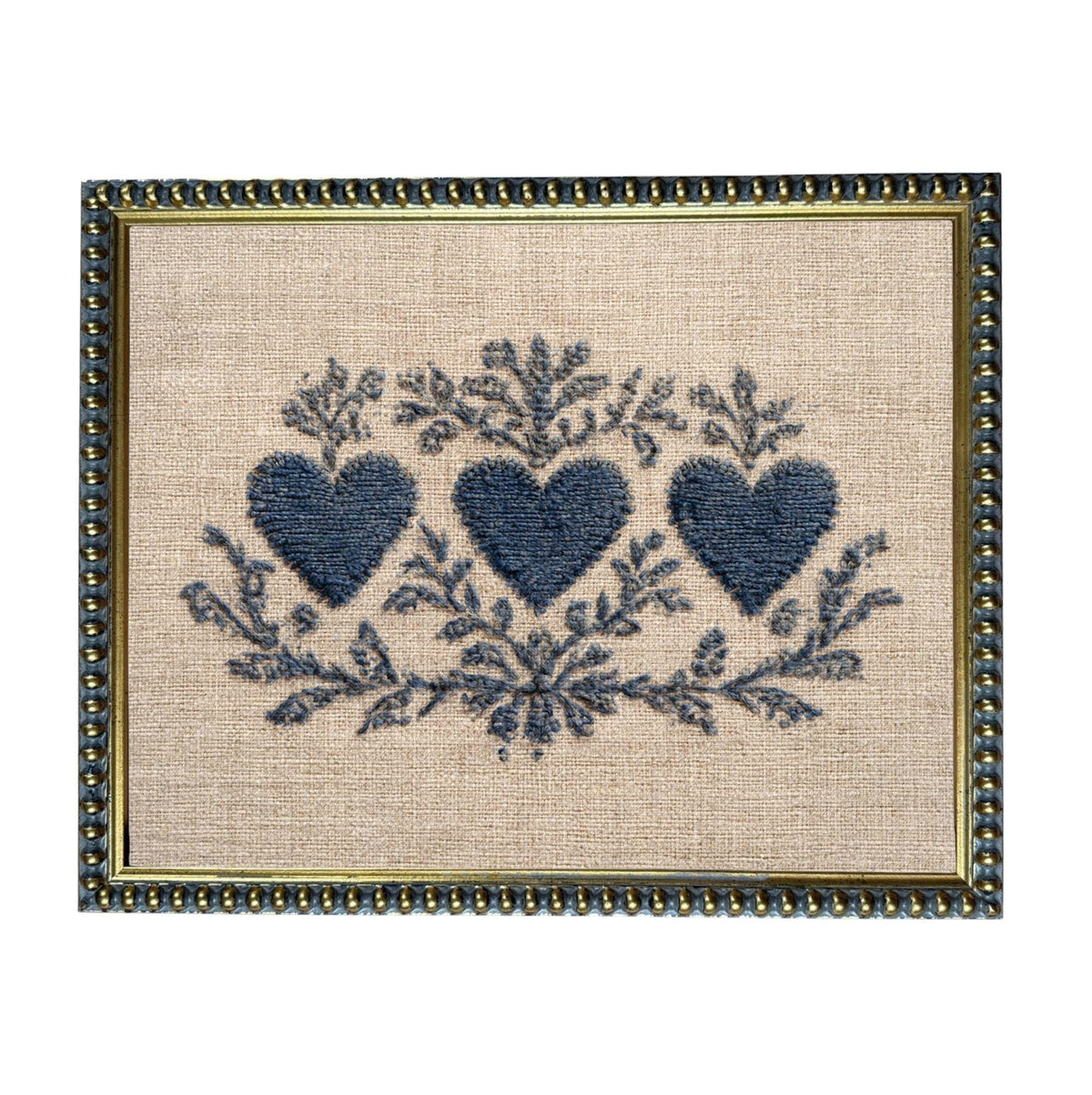a framed embroidered design with three blue hearts and floral elements.