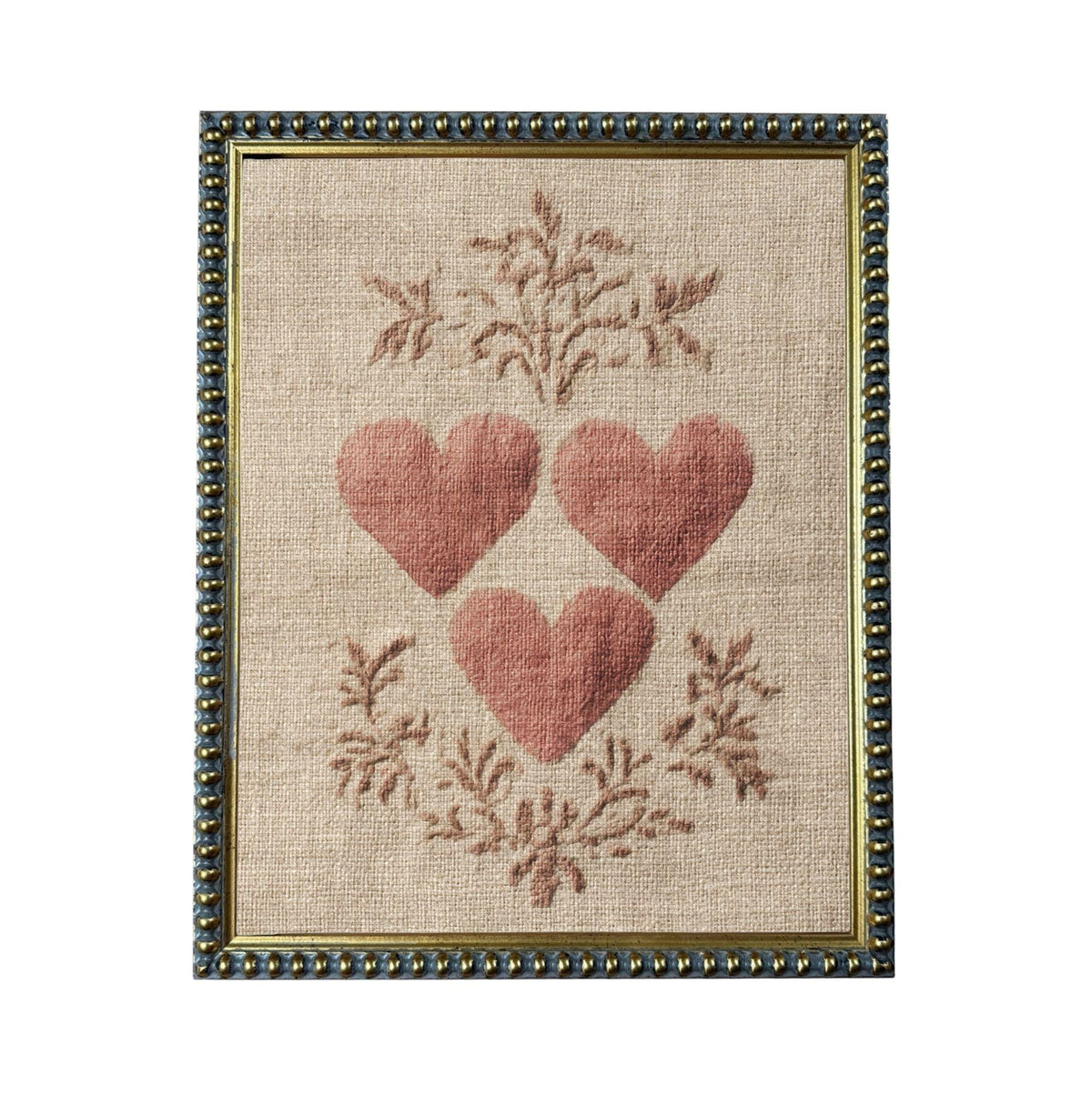 a framed piece of artwork with a beige background and a border. The artwork is a close-up of three red hearts arranged in a triangular formation, surrounded by a floral design.