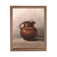 A brown ceramic pitcher with a handle, sitting on a wooden surface against a neutral background.