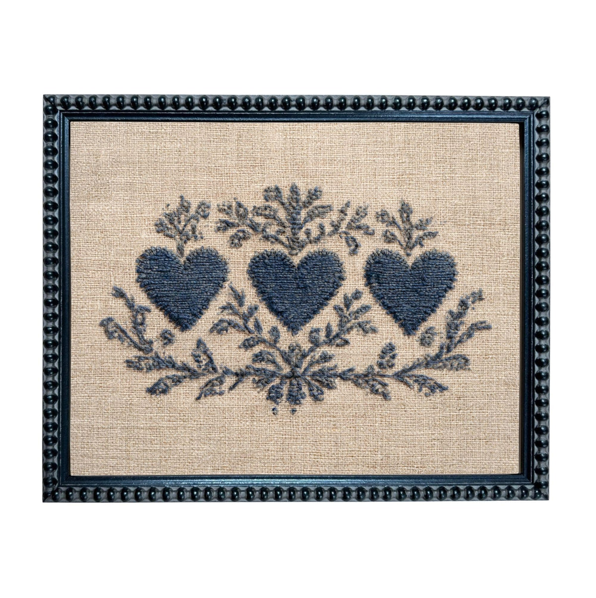 a framed embroidered design with three blue hearts and floral elements.