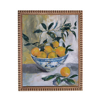 a bowl filled with oranges, surrounded by green leaves, placed on a table.